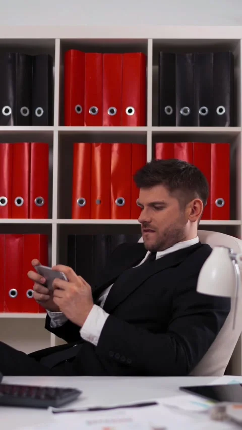 Vertical of businessman playing in game on the iphone Stock Footage 305497744