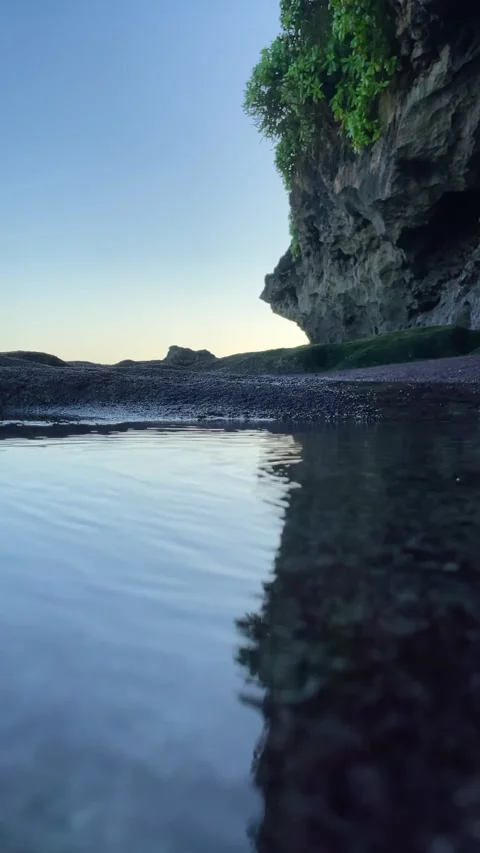 Vertical Calm Ocean Water by Dark Rocky Coastal Cliff in Bali Stock Footage 337336666