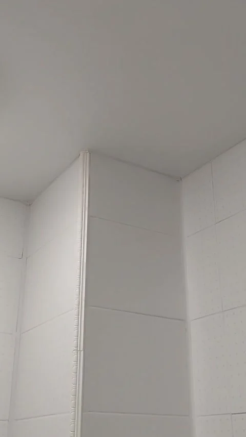 Vertical camera movement across white tiled interior corner and ceiling surface Stock Footage 346933230