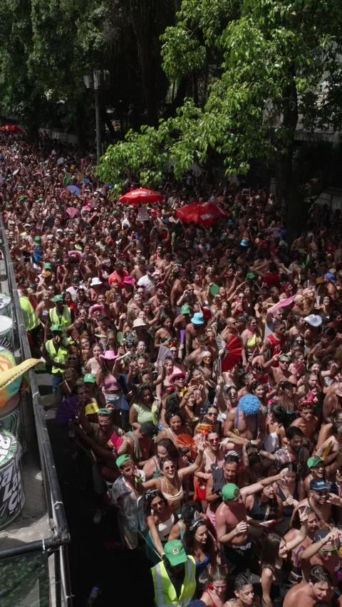 Vertical camera pans over a dense street crowd dancing during Rio de Janeiro Stock Footage 336589890
