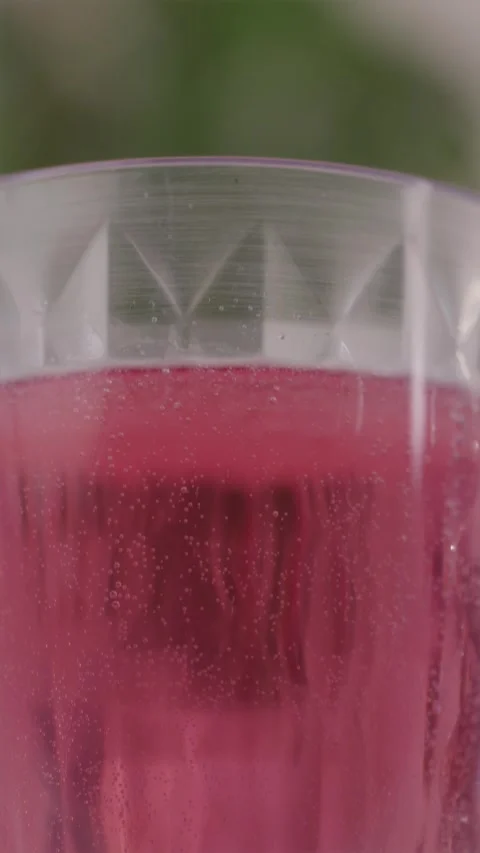 Vertical camera tilt up showing a tall glass with red fizzing drink Stock Footage 332724595