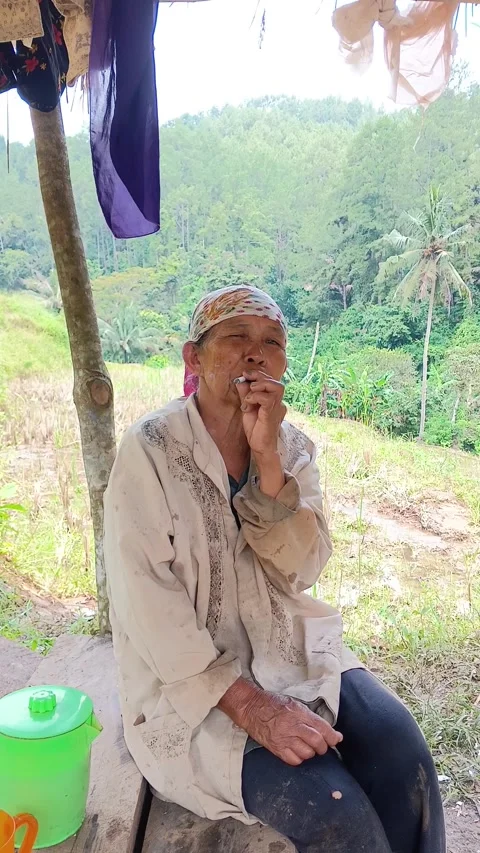 Vertical Candid Elderly Female Farmer Smoking Cigarette and Relaxing at Farm Stock Footage 335019435