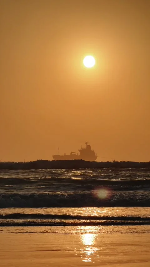 Vertical Cargo Ship Silhouette at Sunrise view from the Beach with waves on the Stock Footage 342583032
