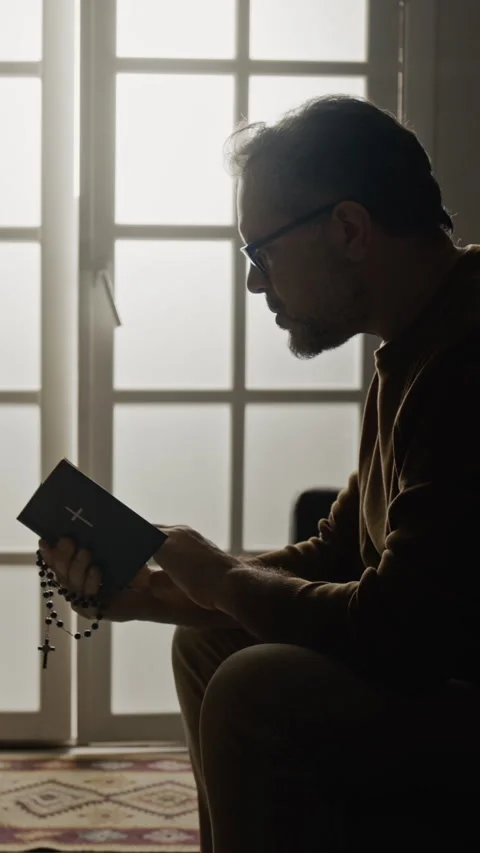 Vertical of Catholic Mature Man with Prayer Beads Reading Scripture Видео 327460934