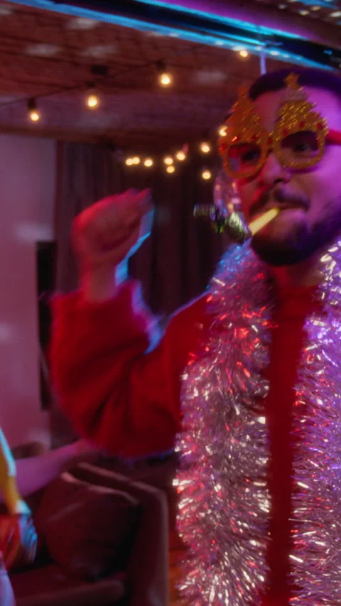 Vertical of Cheerful Man Dancing with Party Horn at Christmas Celebration Stock Footage 344398153