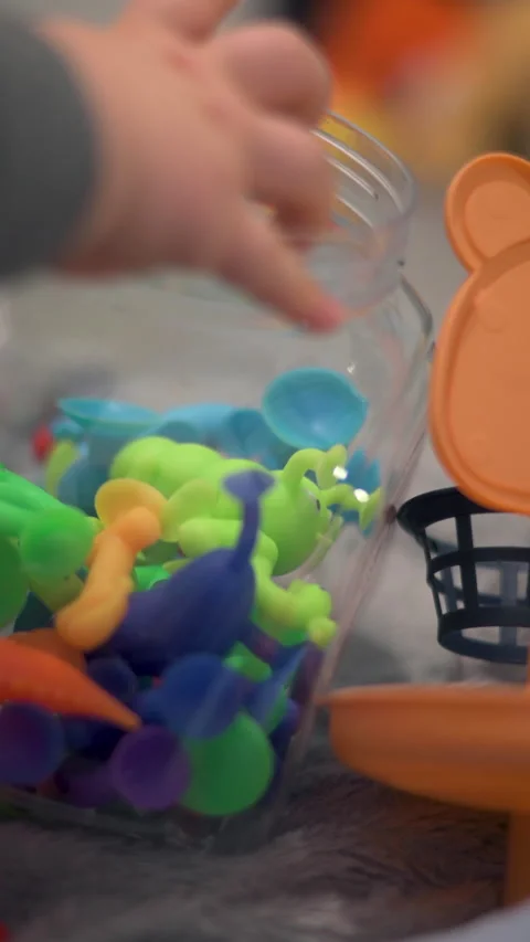Vertical Child And Parent Dropping Colorful Rubber Suction Toys In Clear Jar Video stock 330972415