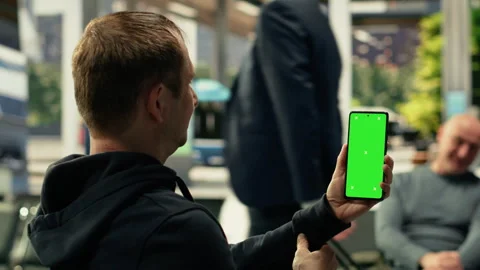 Vertical chroma key on mobile phone held by black man in busy bus station Stock Footage 334730538
