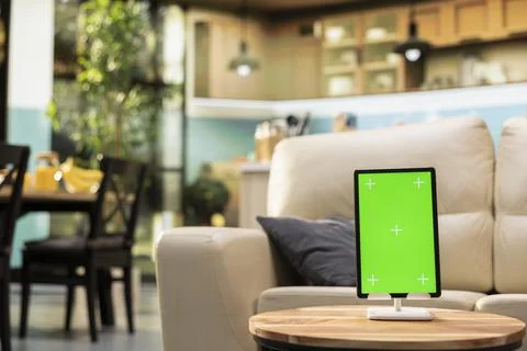 Vertical chroma key tablet, cozy open space, empty wooden table in living room Stock Photos