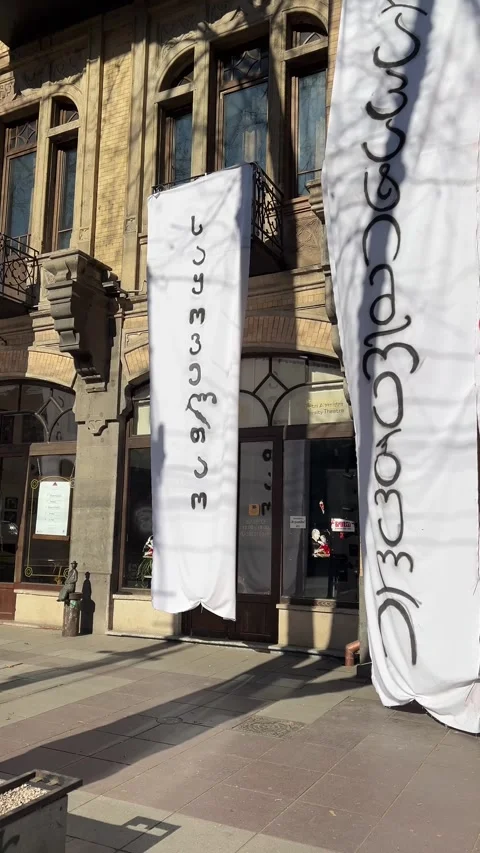 Vertical city 4K video. White banners with Georgian letters on theater building Stock Footage 326826495