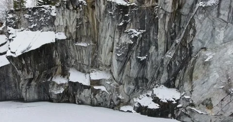 Vertical climb over a marble rock near a frozen marble lake - aerial shot Stock Footage 170558442