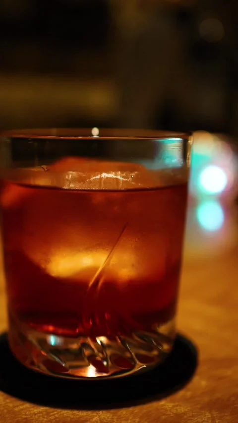 Vertical Close Up of Amber Cocktail with Ice in Dim Lighting Stock Footage 326401538