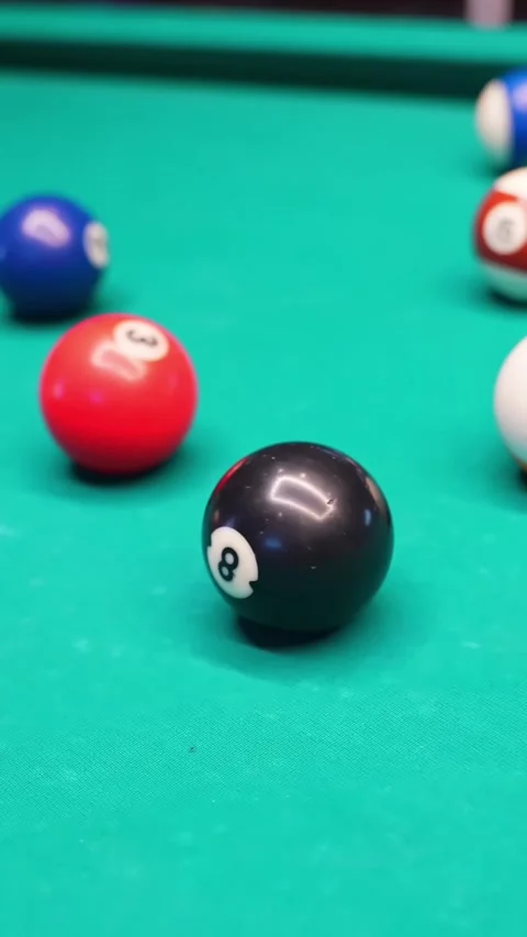 Vertical close-up of black 8 ball on green felt with colorful billiard balls Video stock 327889601