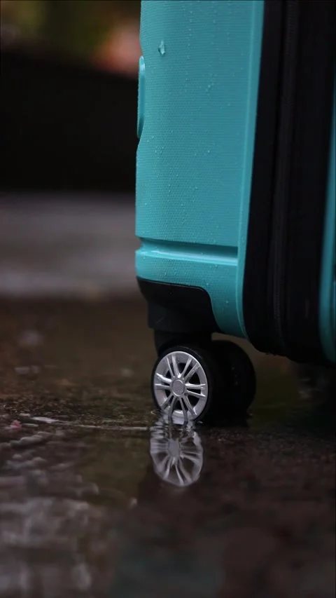 Vertical close-up of blue suitcase wheels on wet pavement in autumn rain da.. Stock Footage 292984224