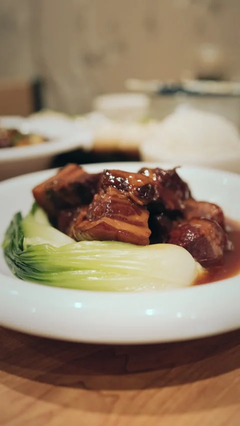 Vertical close-up of braised pork belly with bok choy on white restaurant plate Stock Footage 333897814