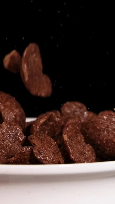 Vertical Close Up of Chocolate Cereal Falling into White Bowl Vídeos de archivo 329740871