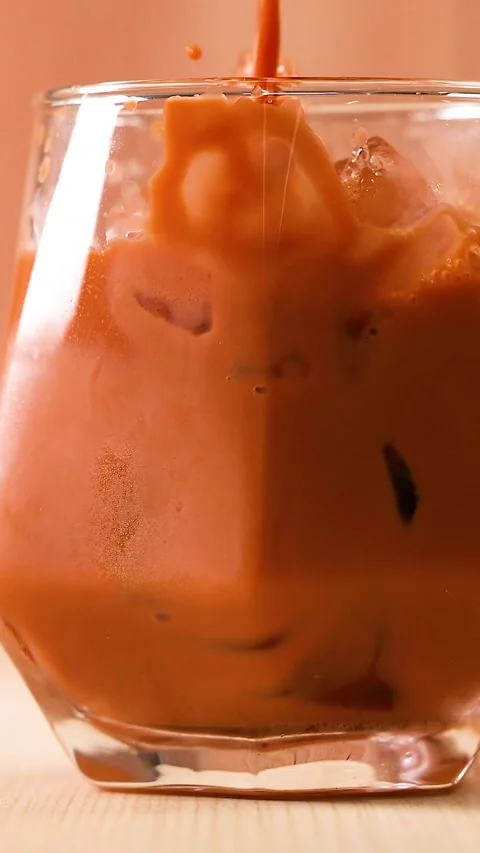 Vertical Close Up of Creamy Orange Tea Pouring Over Ice Stock Footage 329265150