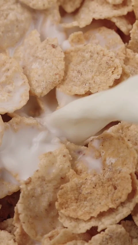 Vertical close-up of crispy gluten-free cereal flakes with milk being poured Stock Footage 318475451