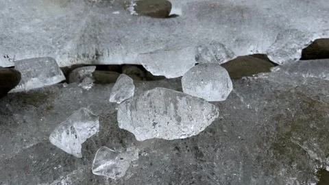Vertical Close Up of Crystal Clear Ice Chunks on Rocky Lake Shore Video stock 328473534