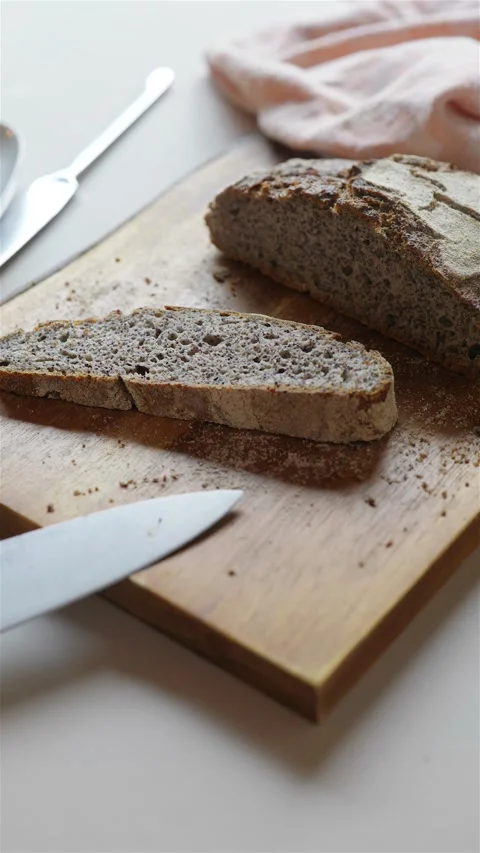 Vertical close up of cut fresh local rye bread on wooden cutting board 動画素材 223691200