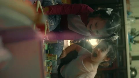 Vertical close-up of cute little sisters are playing together. Happy girls at Stock Footage 146077345