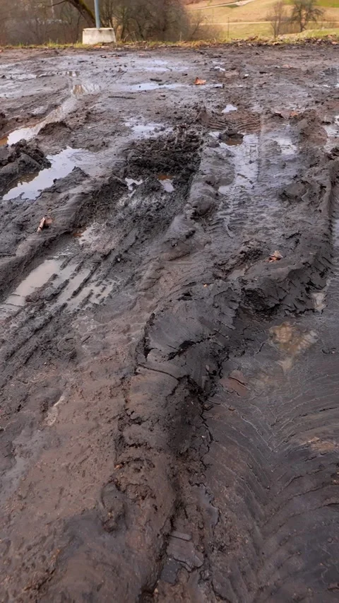 Vertical close-up of deep muddy vehicle ruts with standing water on a damaged Stock Footage 333650247