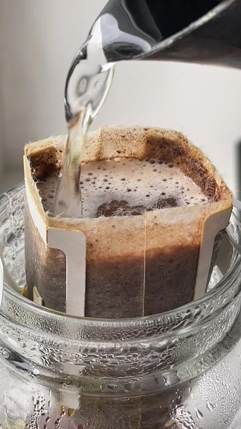 Vertical close up of a drip coffee bag full of hot water, preparation of filt Vidéo 272158163