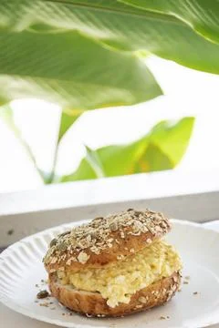 Vertical close up of egg salad bagel sandwich on white plate Stock Photos