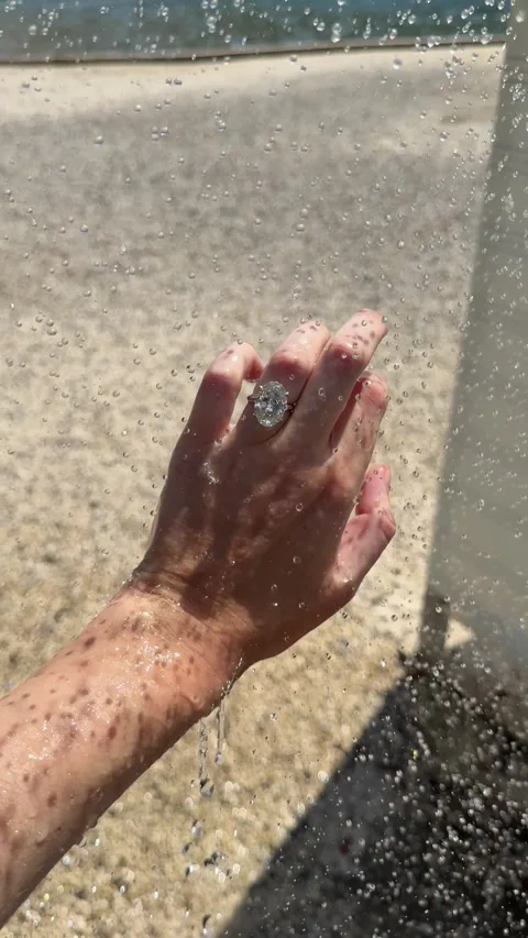 Vertical close up of engagement ring with water raining down in sun 스톡 동영상 319450964
