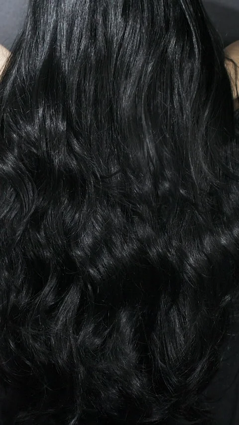 Vertical close-up of female model long black curly hair texture in slow motion Stock Footage 320153542