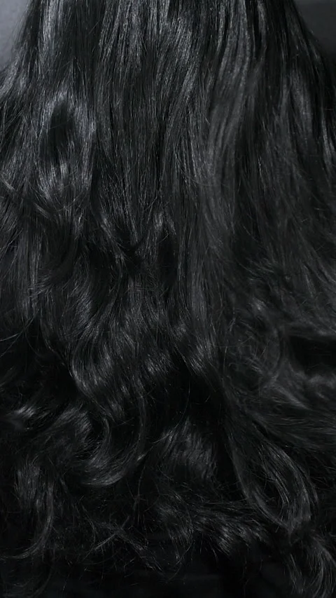 Vertical close-up of female model long black curly hair texture in slow motion Stock Footage 321444679