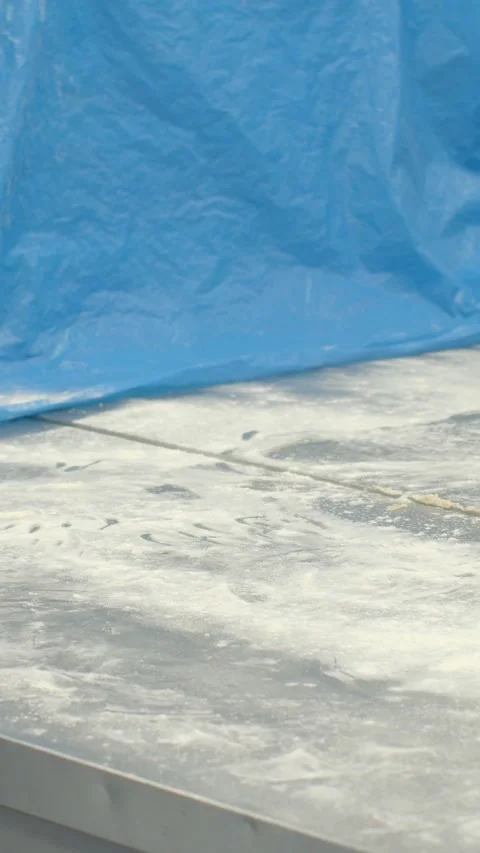 Vertical close-up of flour-dusted bakery worktable with tarp and crates, with Видео 344574068