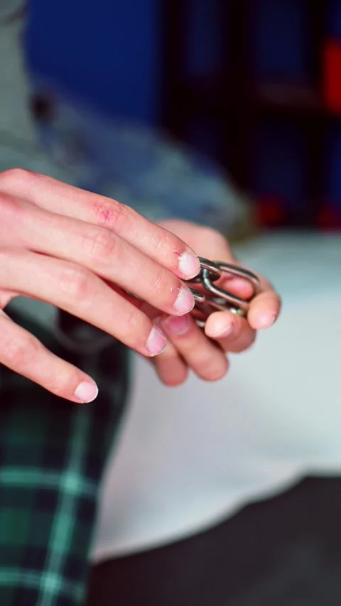 Vertical close up footage on a person's hands trying to solve a metal puzzle. Stock Footage 327027369