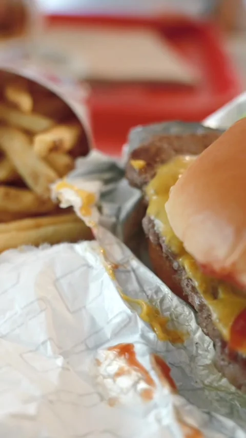 Vertical Close up of fresh combo with hamburger and french fries on a table in a Stock Footage 312586839