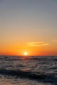 Vertical close up of glowing sun setting over ocean horizon Stock Photos