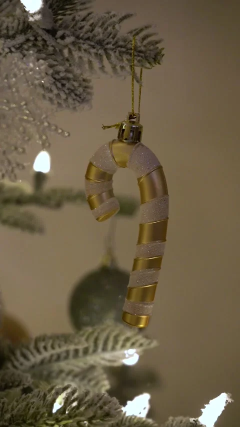 Vertical close up of gold and white glittered candy cane ornament hanging on Stock Footage 327304619