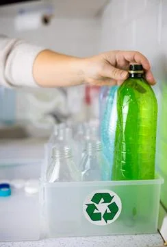 Vertical. Close-up. A hand puts a plastic bottle into a box with a recycling Stock Photos