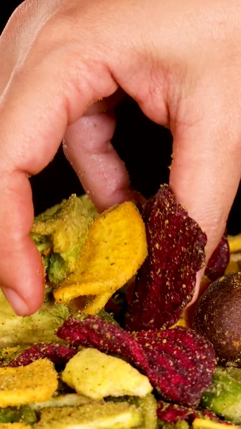 Vertical Close-Up of Hand Selecting Mixed Dried Vegetable Chips Stock Footage 327768085
