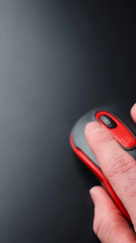 Vertical close-up of a hand using a red and black computer mouse on a dark desk Stock Footage 331322695