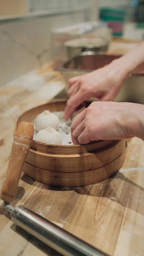 Vertical close-up of hands arranging dumplings in a bamboo steamer basket Stock-Footage 333893155