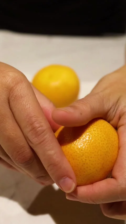 Vertical Close Up of Hands Peeling a Fresh Orange Stock Footage 325828063