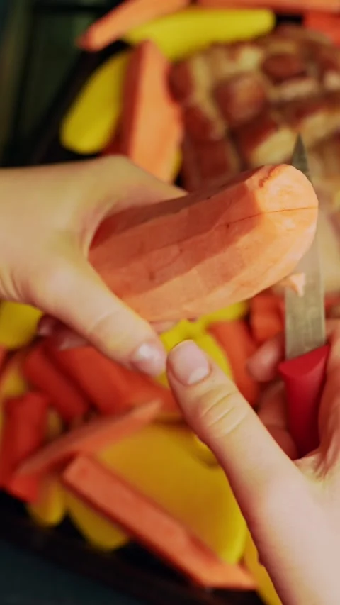 Vertical close-up of hands quartering sweet potatoes and mixing carrots and Stock Footage 331107354