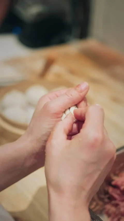Vertical close-up of hands shaping and sealing a Chinese steamed dumpling bun Video stock 333897283