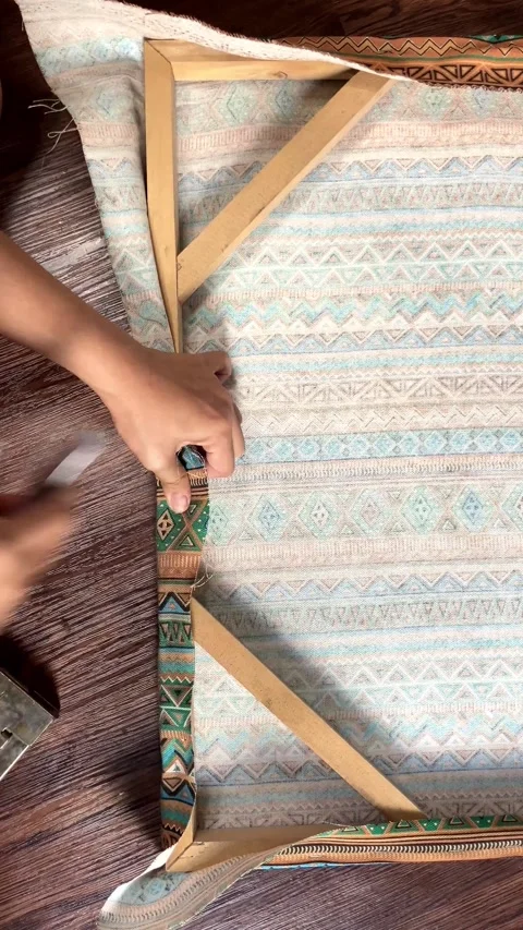 Vertical close up of hands stretching patterned canvas on wooden frame with Stock Footage 345647109