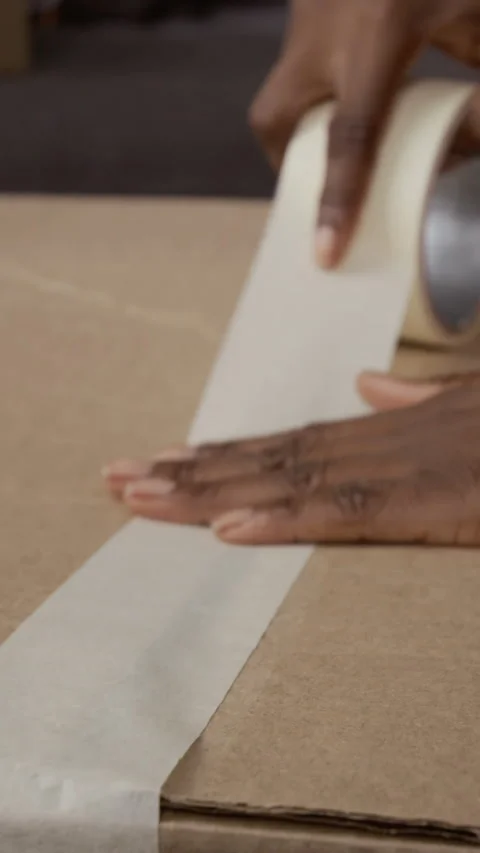 Vertical Close-up of Hands Taping Box after Packing Up Unnecessary Clothes Stock Footage 335155573