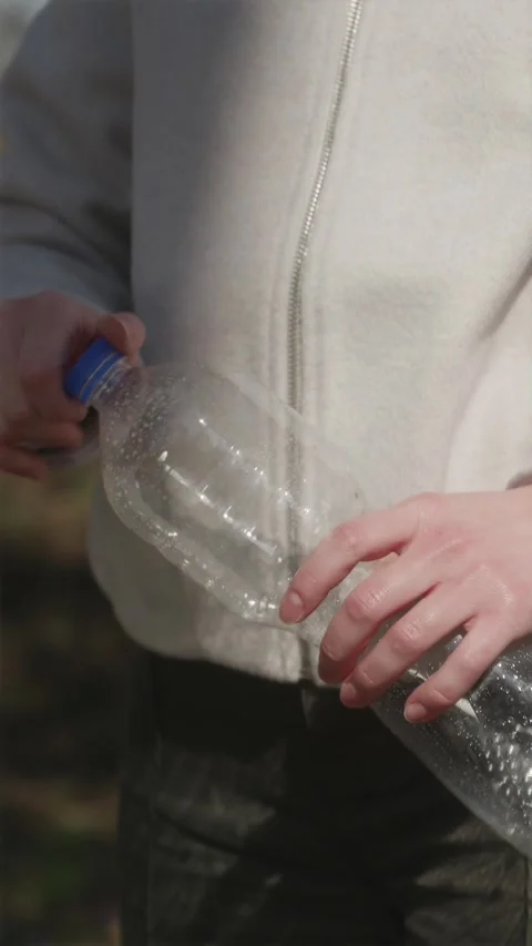 Vertical close up of hands twisting cap and littering plastic bottle Stock Footage 333118395