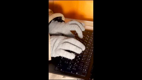 Vertical close up of hands in winter gloves typing on a laptop during blackout Stock Footage 328063040