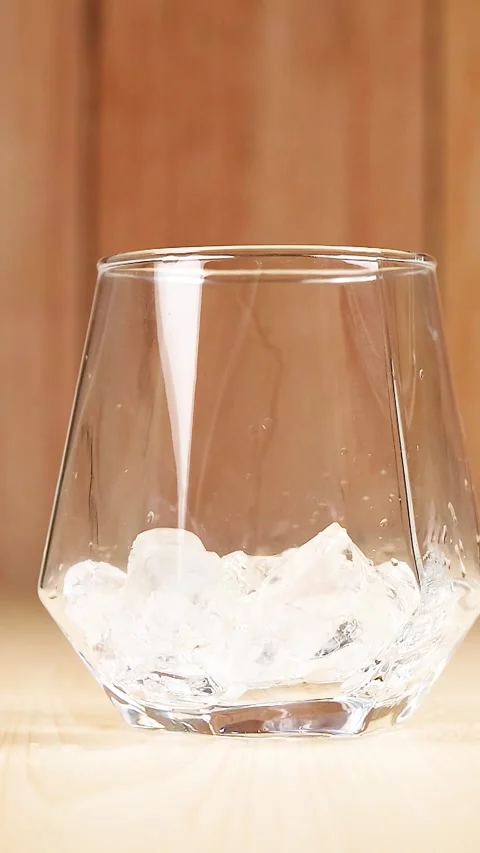 Vertical Close Up of Ice Cubes Dropping into a Clear Glass Stock Footage 329466022