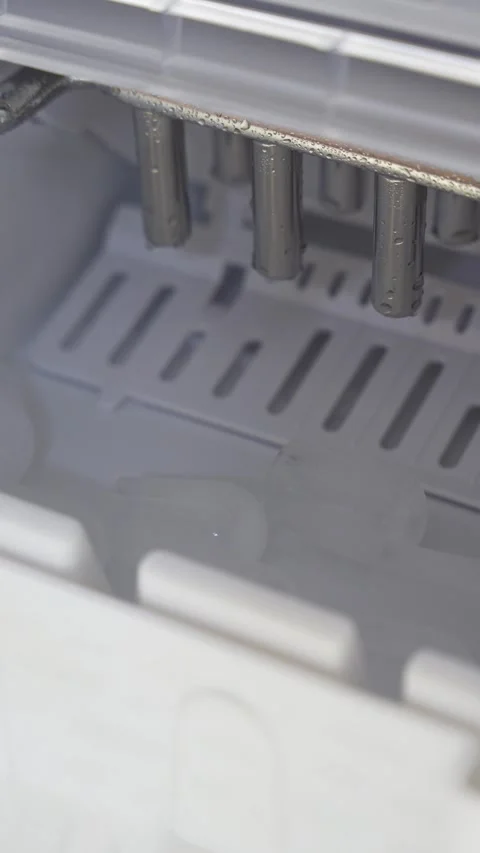 Vertical close-up inside a portable ice maker, showing fresh ice cubes Stockbeeldmateriaal 335461917