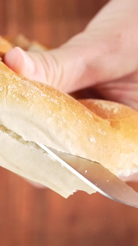 Vertical Close-Up Knife Cutting Soft Bun in Half on Wooden Background  Slow.. Stock Footage 312169249