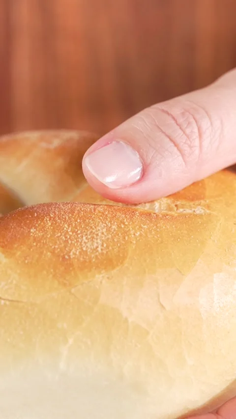 Vertical close-up macro shot of female hand holding freshly baked soft bun... Stock Footage 312169146
